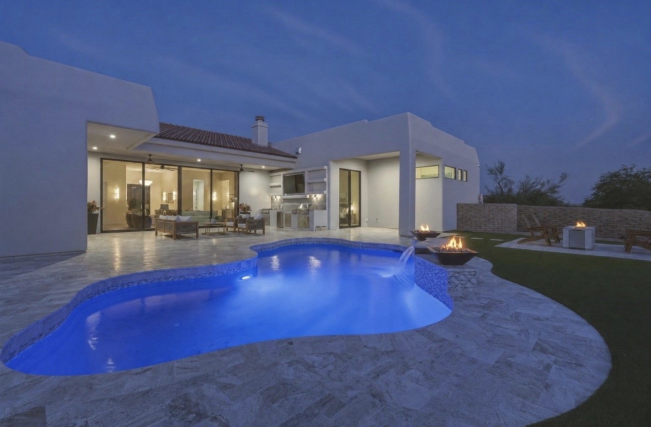 Backyard pool lit up at night beside a Phoenix home