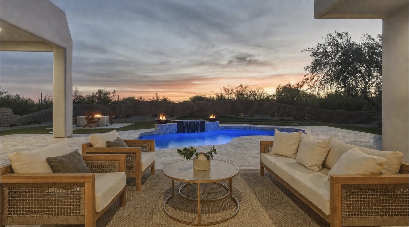 A backyard pool glowing blue at dusk, seen from a covered patio in Phoenix, Arizona